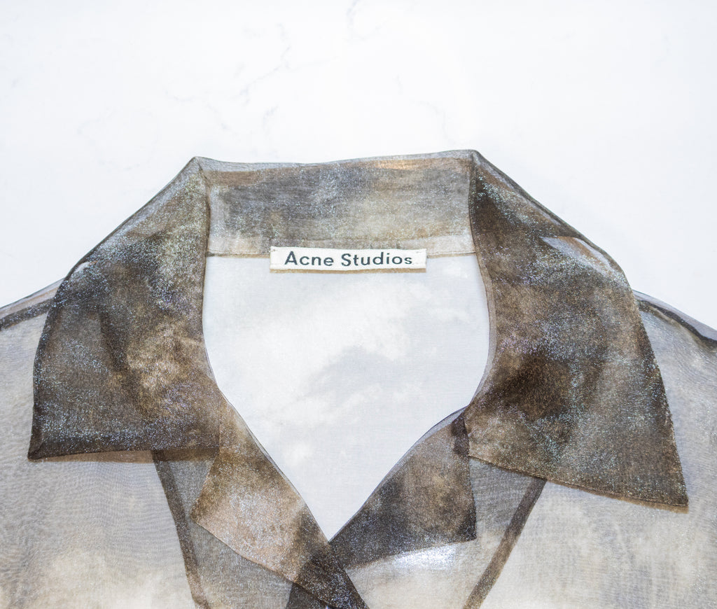 Close-up of a sheer organza shirt collar with a metallic bronze and gold shimmer, featuring an Acne Studios label at the inner neck.